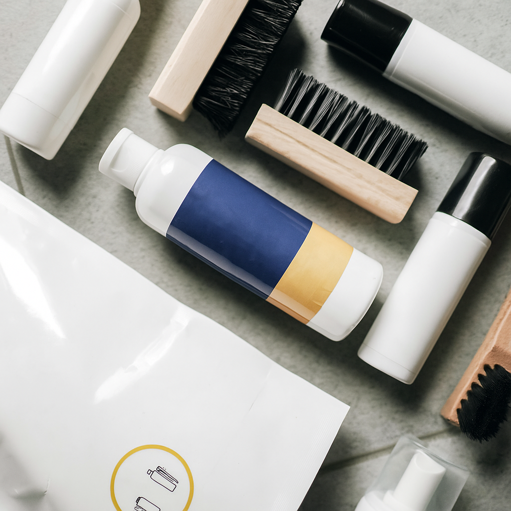 An assortment of products featuring a brush,shoe soap, and a bottle of shampoo for Odysshoes shoe cleaner